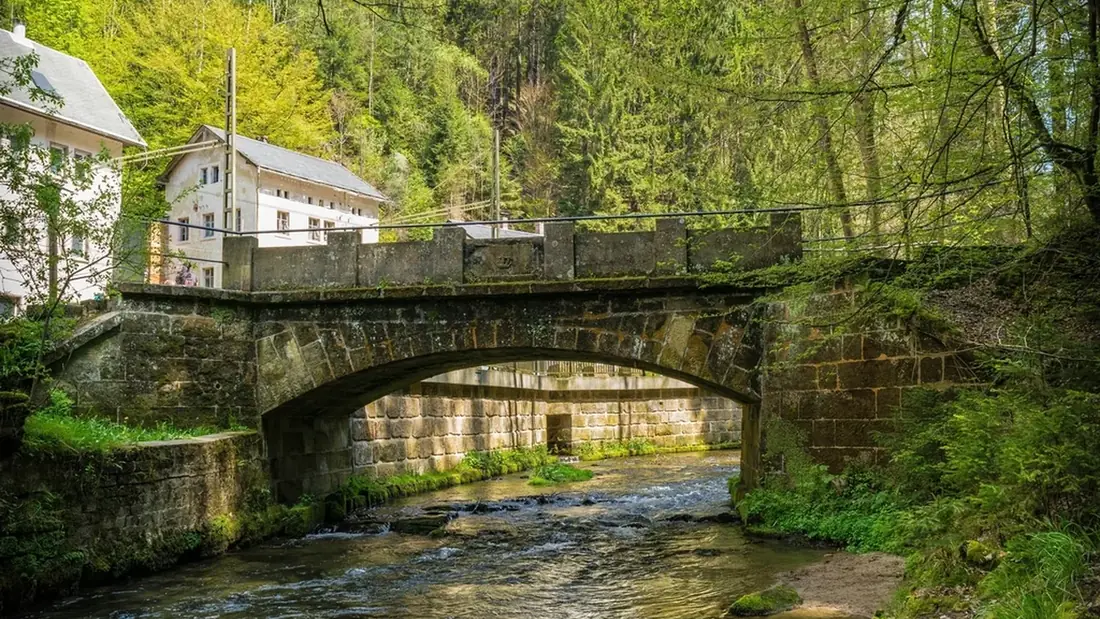 A stone arch bridge carrying a road over a shallow river